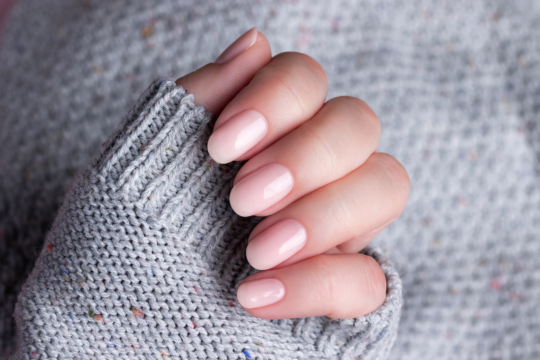 Hand in sweater with nude nails